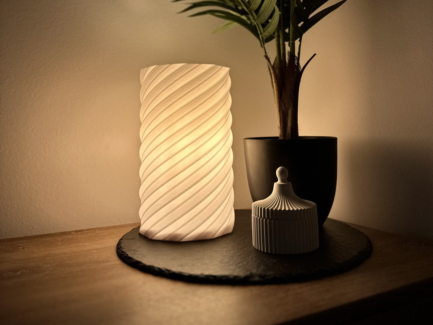 Stilvolle Tischlampe mit warmweißem, dimmbarem Licht, Spiralschirm, arrangiert mit Pflanze und Deko-Dose