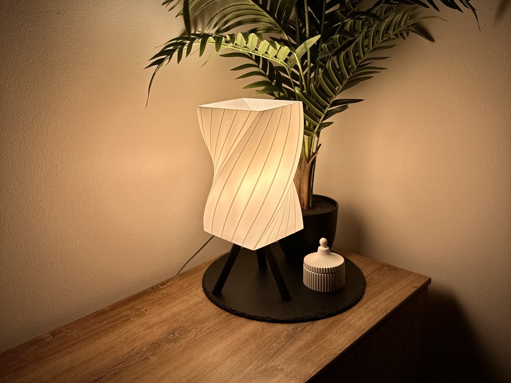 Design-Tischlampe mit eckigem Schirm, geprägt von eleganten, diagonalen Wellen, dekoriert mit Dose und Pflanze