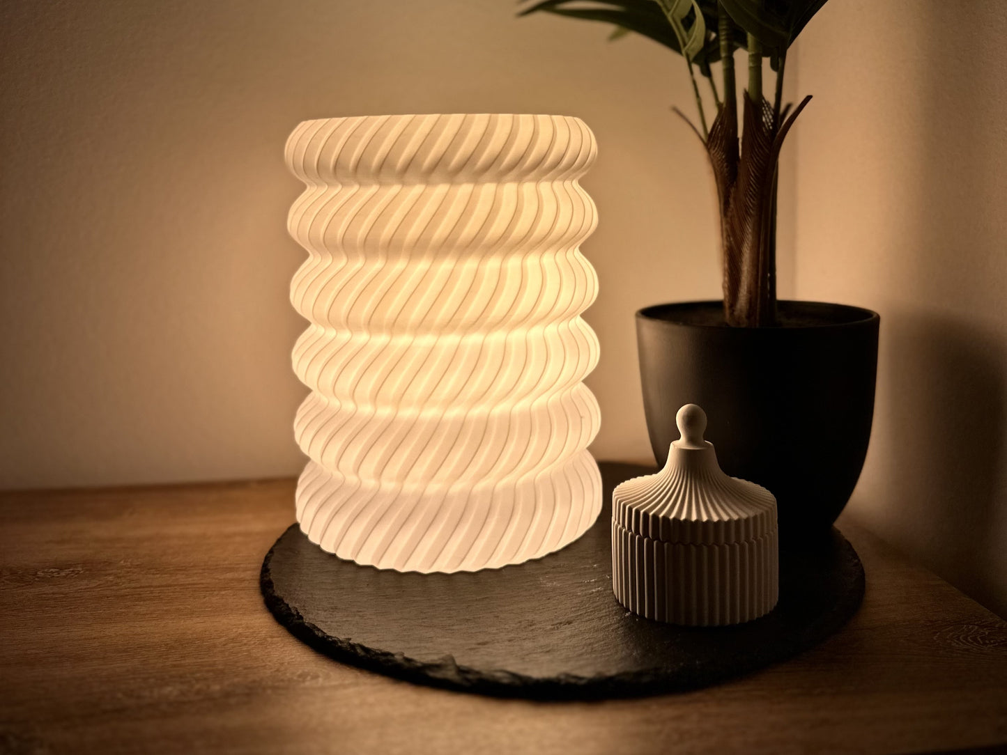 Moderne, dimmbare Tischlampe, warmweißem Licht, spiralförmigem Lampenschirm mit Pflanze und Dose.