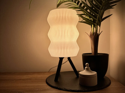 Minimalistische Dimmbare Tischlampe mit wellenförmigem Schirm auf dreibeinigem Ständer, warmweißes licht, neben Deko